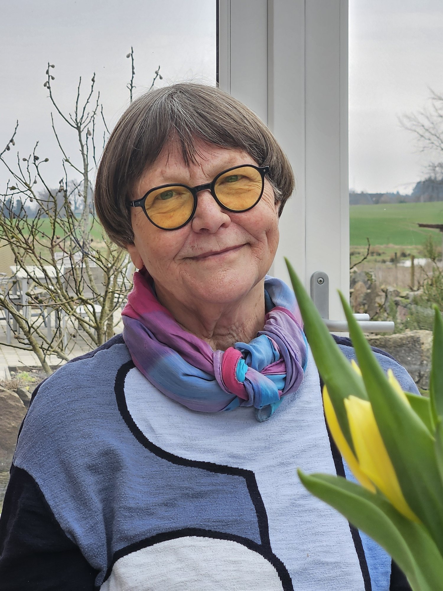 Mormor med gule briller og farverigt tørklæde